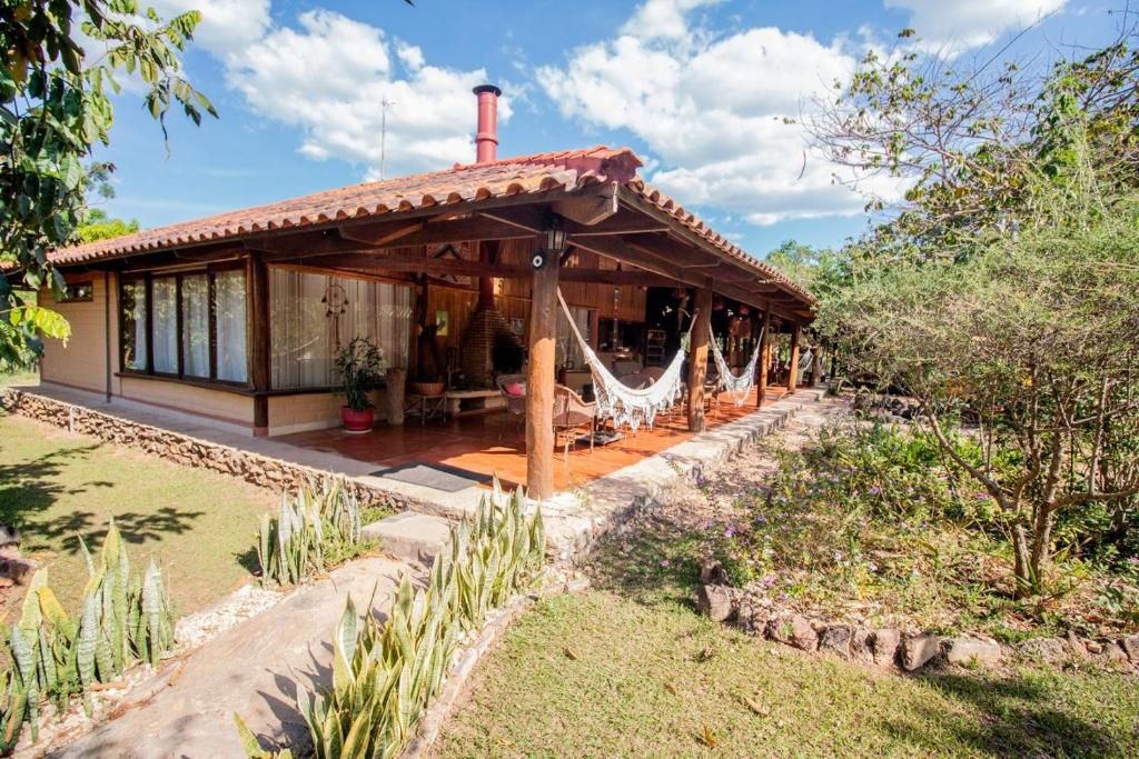 Casa-sede com telhado colonial, varanda com redes e jardim